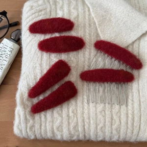 Rotes Plüsch-Haarclip-Set mit Haarkämmen auf weißem Strickpullover für festliche Winterstimmung