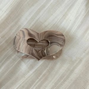 Detail of heart-shaped marble acetate hair claw clip with dark khaki flow pattern