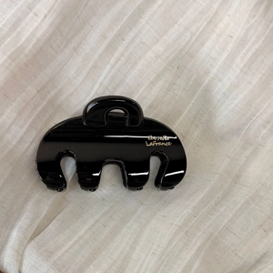 Glossy black hair claw clip with golden Barrette LaFrance text on white fabric