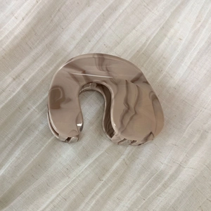 Detailed macro view of beige and dark brown marbled texture on polished hair claw clip