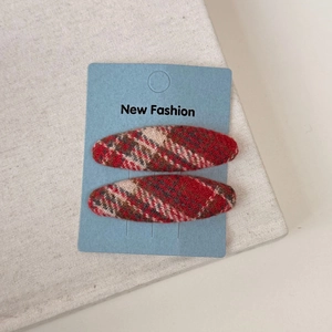 Detailed close-up of red plaid fabric hair clips on a New Fashion display card