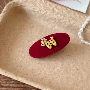 Dettaglio del fermaglio in velluto rosso con barboncino dorato e strass scintillanti