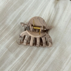 Macro detail of marble pattern hair claw clip with a strong gold metal spring mechanism