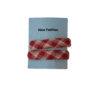 Pair of red and beige checkered tweed hair clips displayed on a professional card