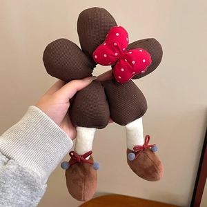 Close-up of plush hair tie with red polka dot bow and brown knit legs design