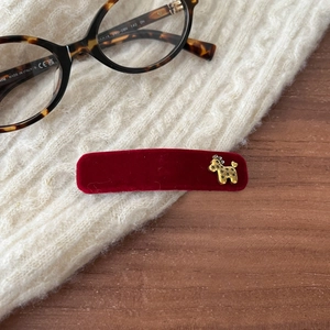 Detail of velvet rectangle hair clip with golden poodle charm on knit background