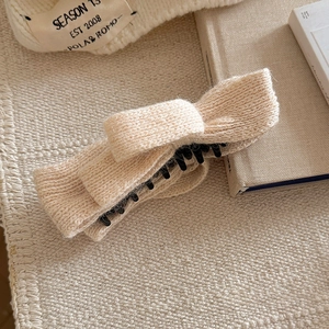 Knitted beige bow hair clip with high ponytail banana clip shown in a cozy winter setting