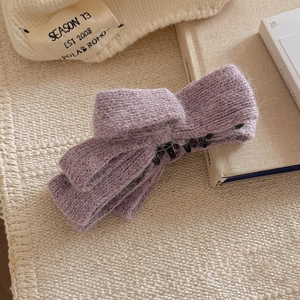 Close-up of purple knitted bow hair clip featuring soft textured yarn and durable inner teeth
