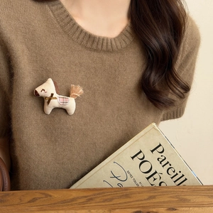 Cute beige fabric horse brooch with brown bow and pink plaid detail on brown sweater
