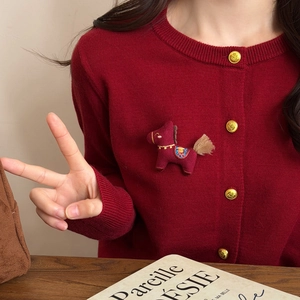 Detail of cute red horse fabric brooch pinned on a burgundy knit cardigan sweater