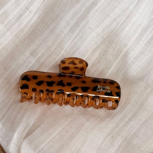 Detail of tortoiseshell hair claw clip with Barrette La France text on linen texture