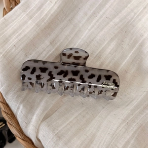 Detail of tortoise shell hair claw clip with golden lettering on soft linen textile