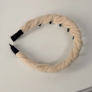 Dettaglio del cerchietto in maglia a treccia beige con denti antiscivolo neri stabili