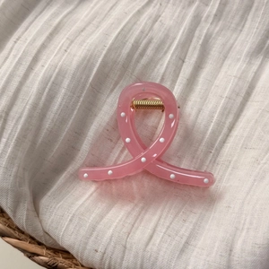 Vue détaillée de la pince à cheveux rose à pois avec finition transparente sur tissu