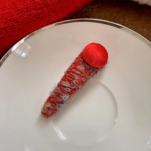 Elegant red plush flower hair clip with handmade knitted texture on a ceramic plate