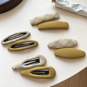 Set of 8 handmade yellow plaid fabric hair clips in various shapes on a white background
