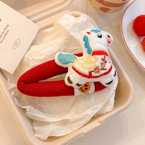 Close-up of a festive red embroidered pony hair clip for children with floral patterns
