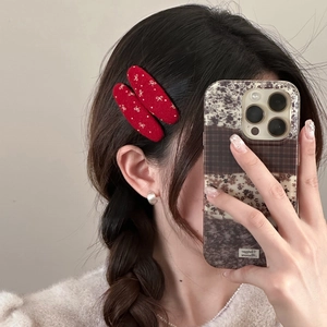 Red oval hair clips with white bow patterns worn on hair for a festive New Year look