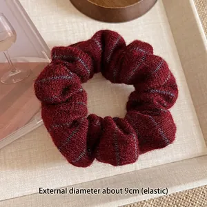 Close-up of a burgundy knitted scrunchie with navy stripes and 9cm outer diameter