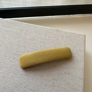 Close-up of yellow plaid fabric hair clip on beige linen background for spring hair styling
