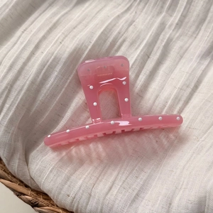 Pince à cheveux rose à pois blancs pour femme sur fond de tissu blanc texturé souple