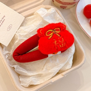Close-up of red plush hair clip with gold bow and Fu embroidery in a gift box