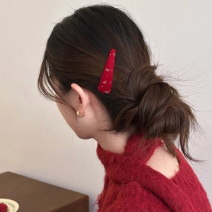 Red snap clip with gold bow embroidery on fabric, worn on model for a festive look