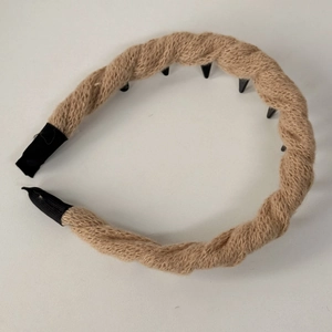 Dettaglio della trama in maglia intrecciata marrone e denti antiscivolo del cerchietto