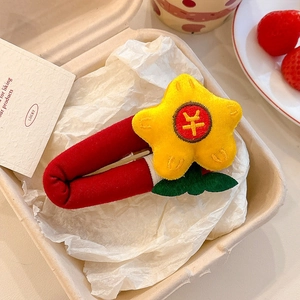 Detail of red knit star hair clip with yellow plush star and currency symbol decoration