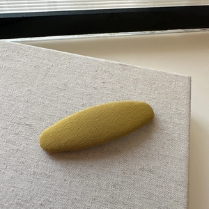 Detail view of mustard yellow plaid fabric texture on a long oval hair clip for women