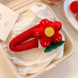 Close-up of handmade red fabric flower hair clip with yellow stitching and green leaf