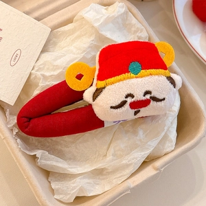 Detailed top view of cartoon God of Wealth plush hair clip in a festive gift box setup