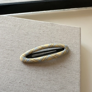 Detailed view of yellow plaid fabric hair clip with elegant woven texture and sturdy metal grip