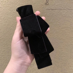 Close-up of a large black velvet bow hair clip showing soft fabric texture and layers