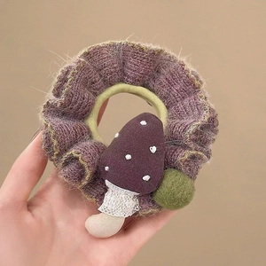 Detail of purple knitted scrunchie with mushroom plush and green pompom detail