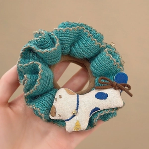 Detailed close-up of handmade blue knitted scrunchie with cute puppy doll attachment