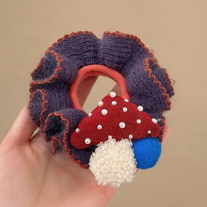 Knitted pony mushroom scrunchie with orange scalloped edges and cozy winter texture
