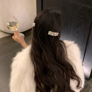 Detailed view of two sparkling rhinestone rectangle hair clips on long wavy hair