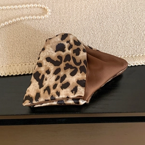 Macro detail of leopard print satin hair scrunchie with smooth silk-like texture