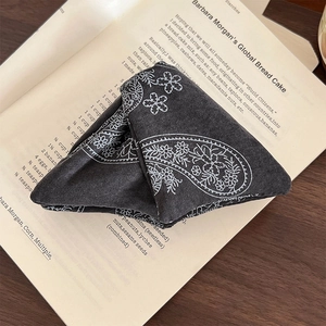 Vintage paisley pattern triangular hair claw clip made of dark grey fabric on a wooden table