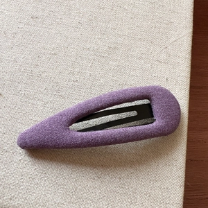 Macro detail of lavender purple woven fabric texture on a snap hair clip with metal base