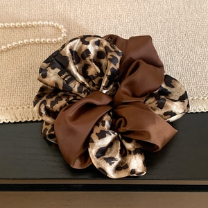Detail view of brown leopard print satin scrunchie with smooth texture and pearl accents