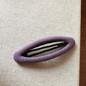 Detailed view of the purple fabric-wrapped BB hair clip on a neutral linen background