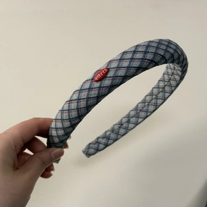 Close-up of blue and gray plaid fabric headband with thick padded design and red oval tag