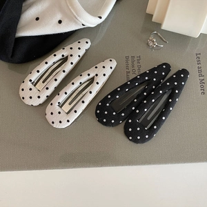 Retro polka dot fabric BB hair clips set in black and white on a textured background