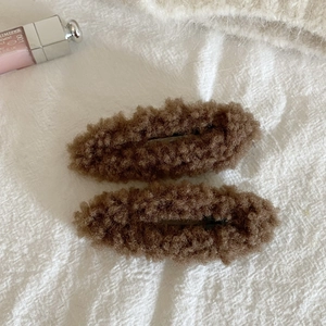 Close-up of two brown plush teddy fabric oval hair clips for autumn and winter styling