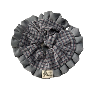Blue and grey plaid fabric scrunchie with pleated texture and a small handmade woven label