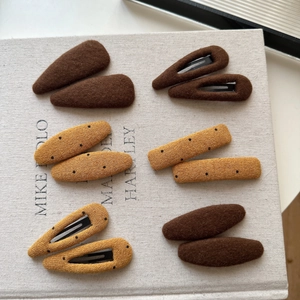 12-piece brown and yellow handmade knitted hair clips set on linen textured book