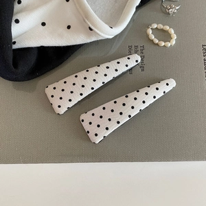 Detailed macro view of trendy fabric polka dot hair clips with a white textile texture