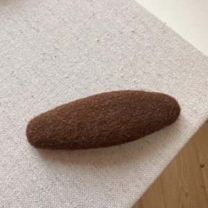 Close-up of deep brown wool felt hair clip with soft texture for autumn winter fashion